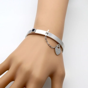 Polished stainless steel heart charm bracelet with forever love engraving on a model wrist