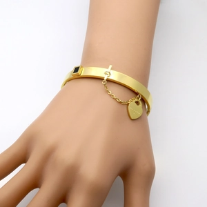 Gold stainless steel bangle with black square inlay and heart charm on a model hand