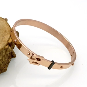 Macro detail of rose gold rivet belt buckle bracelet with mirror-polished steel finish