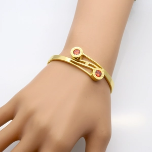 Gold-plated stainless steel cuff bracelet featuring roman numerals and red zircon stones