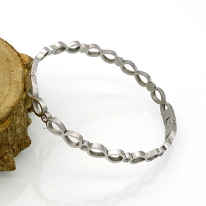 Détail macro du bracelet infini en acier inoxydable argenté serti de zircons brillants