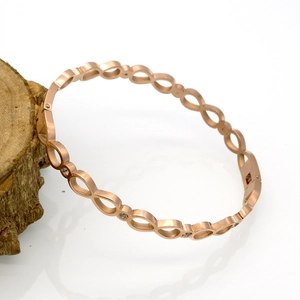 Détail macro du bracelet infini en or rose serti de pierres en zircone étincelantes