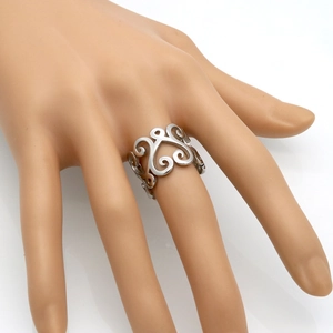 Wide silver hollow ring featuring heart and scroll patterns on a white background