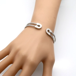 Detailed macro view of a silver safety pin style stainless steel open bangle bracelet
