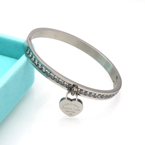 Stainless steel bangle with heart charm and sparkling zircon stones on a blue gift box