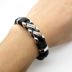 Close-up of men's punk leather bracelet featuring a silver polished metal flame charm