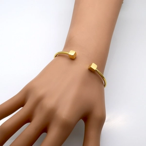 Detail of 18k rose gold plated open cuff bracelet with cubic ends on woman's wrist