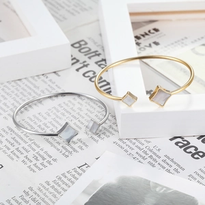 Polished stainless steel bangle with star-shaped shell inlay in gold and silver finish
