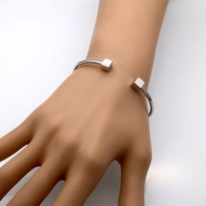 Detailed shot of open stainless steel cuff bracelet with geometric cube ends on model