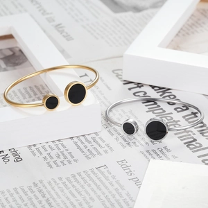 Close-up of gold and silver stainless steel open bangles with circular black shell inlay
