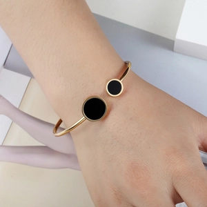 Minimalist gold-plated stainless steel open bangle featuring black circular geometric shell inlay