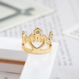 Bague couronne dorée avec cœurs ajourés et trois zircons brillants sur support blanc