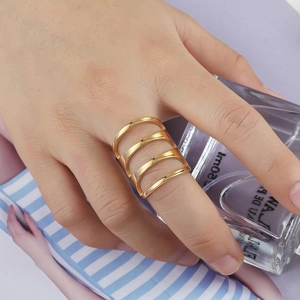 Anello largo dorato lucido con design geometrico a quattro strati sulla mano della modella