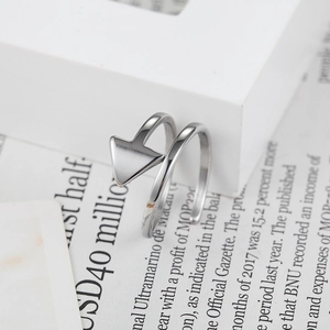 Minimalist silver geometric wrap ring with arrow tip design on newspaper aesthetic backdrop