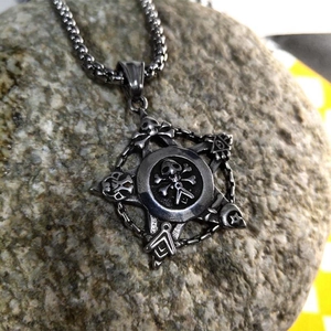 Vintage gothic skull pendant on heavy chain link necklace displayed on natural rock