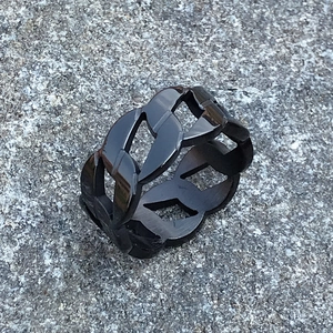Makroaufnahme von matt schwarzem Edelstahl-Kettengliedring auf Stein Hintergrund