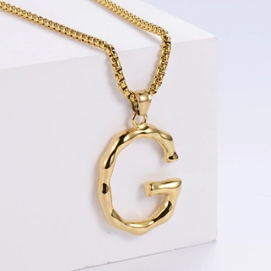 Détail du pendentif lettre G dorée 3D avec texture lave sur une fine chaîne vénitienne