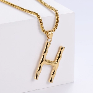 Détail du pendentif lettre H doré avec texture bambou sur une grosse chaîne box