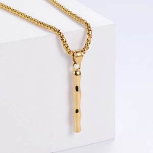 Vue détaillée d'un pendentif doré de style bambou sur une chaîne à maillons carrés