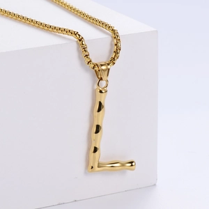 Détail du pendentif lettre L dorée avec texture bambou sur une chaîne box