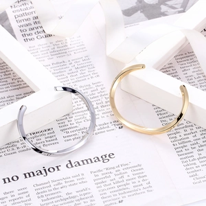 Macro shot of mirror-polished gold and silver Mobius cuff bracelets on white display