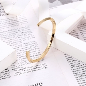 Close-up of polished gold Mobius cuff bracelet on vintage newspaper background