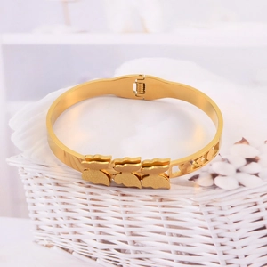 Detail of golden stainless steel bangle featuring matte bear charms and spring hinge