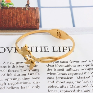 Detail of a gold butterfly open cuff bracelet with crystal inlay on an openwork band