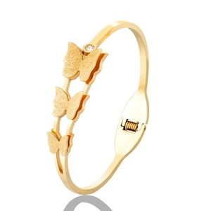Close-up of gold stainless steel bangle featuring matte butterflies and a zircon stone