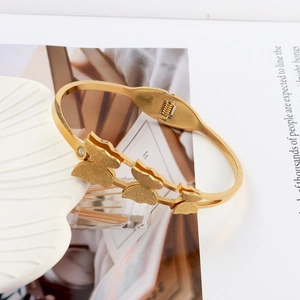 Detailed view of golden stainless steel butterfly bangle with matte finish and zircon