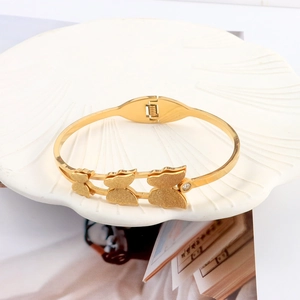 Detailed shot of golden butterfly bangle with matte finish and zircon stone on ceramic tray