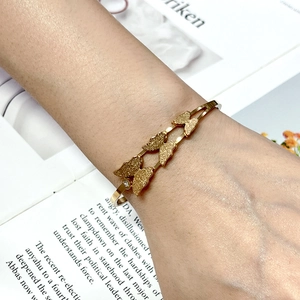Detail of gold butterfly bangle with frosted texture and zircon on English magazine