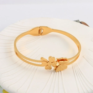 Detail of gold clover and frosted butterfly design on a stainless steel bangle