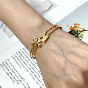 Detail of a gold butterfly and clover bangle with frosted texture on an open band