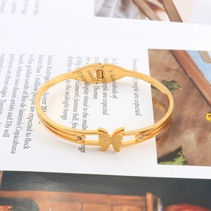 Macro detail of golden butterfly bangle with matte finish and sparkling zircon accents
