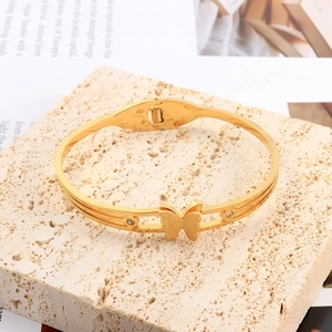 Detail of a gold butterfly bangle featuring matte finish and sparkling zircon accents