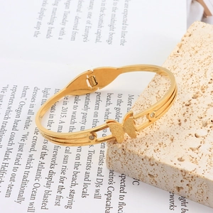 Detail view of gold butterfly bangle with frosted texture and sparkling zircons