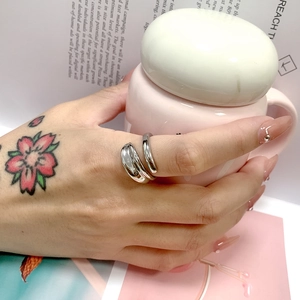 Dettaglio di un anello in acciaio argentato minimalista su una modella con tazza