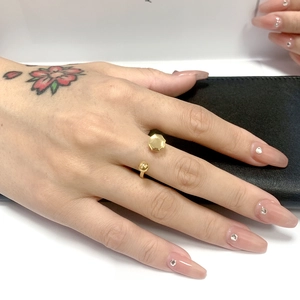 Dettaglio dell'anello dorato con design geometrico aperto e sfera decorativa sulla mano