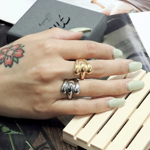 Close-up of chunky gold and silver twisted stackable rings on hands with floral tattoos