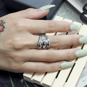 Macro view of liquid-style silver stainless steel ring on model with tattoo
