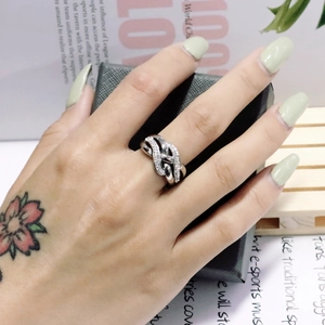 Close-up of a silver twisted knot ring with pavé diamond accents on a model's hand
