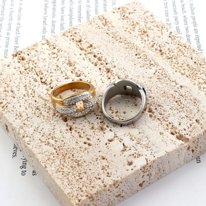 Close-up of gold pig nose chain ring with pavé zircons on textured stone background