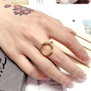 Detailed close-up of 18K gold plated wavy titanium ring worn on model with floral tattoo