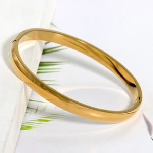 Dettaglio macro del bracciale rigido dorato in acciaio inossidabile con chiusura laterale