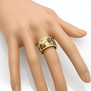 Detailed macro of gold-plated wide band ring featuring multi-colored baguette-cut crystals