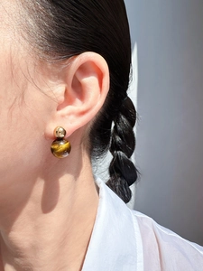 Dettaglio di orecchini vintage con sfera dorata e pietra occhio di tigre marrone