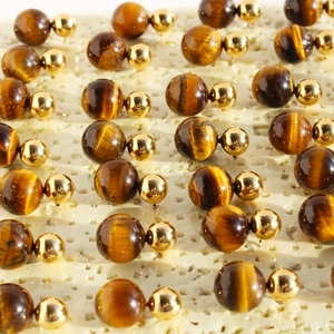 Orecchini vintage con occhio di tigre e sfere dorate su un espositore per gioielli