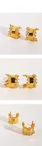 Macro detail of golden C-shaped hoop earrings with irregular lava texture and metallic finish