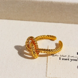 Vintage gold-plated knotted rope ring with adjustable open design on canvas background